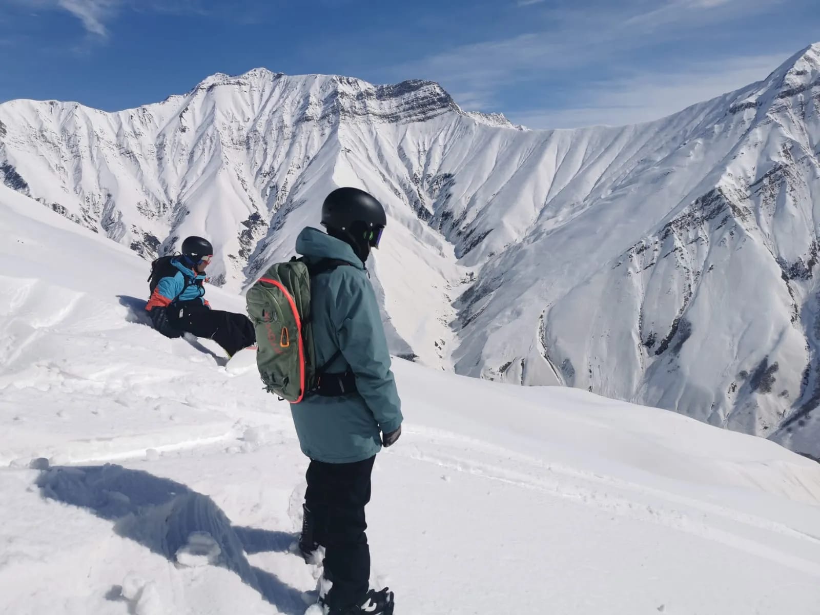 Two snowboarders above a snowy mountain bowl in Gudauri
