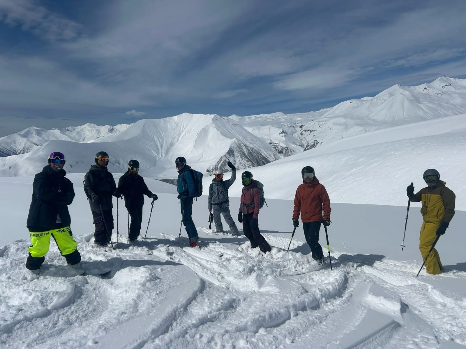 A group of riders spread across a snowy ridge in Gudauri