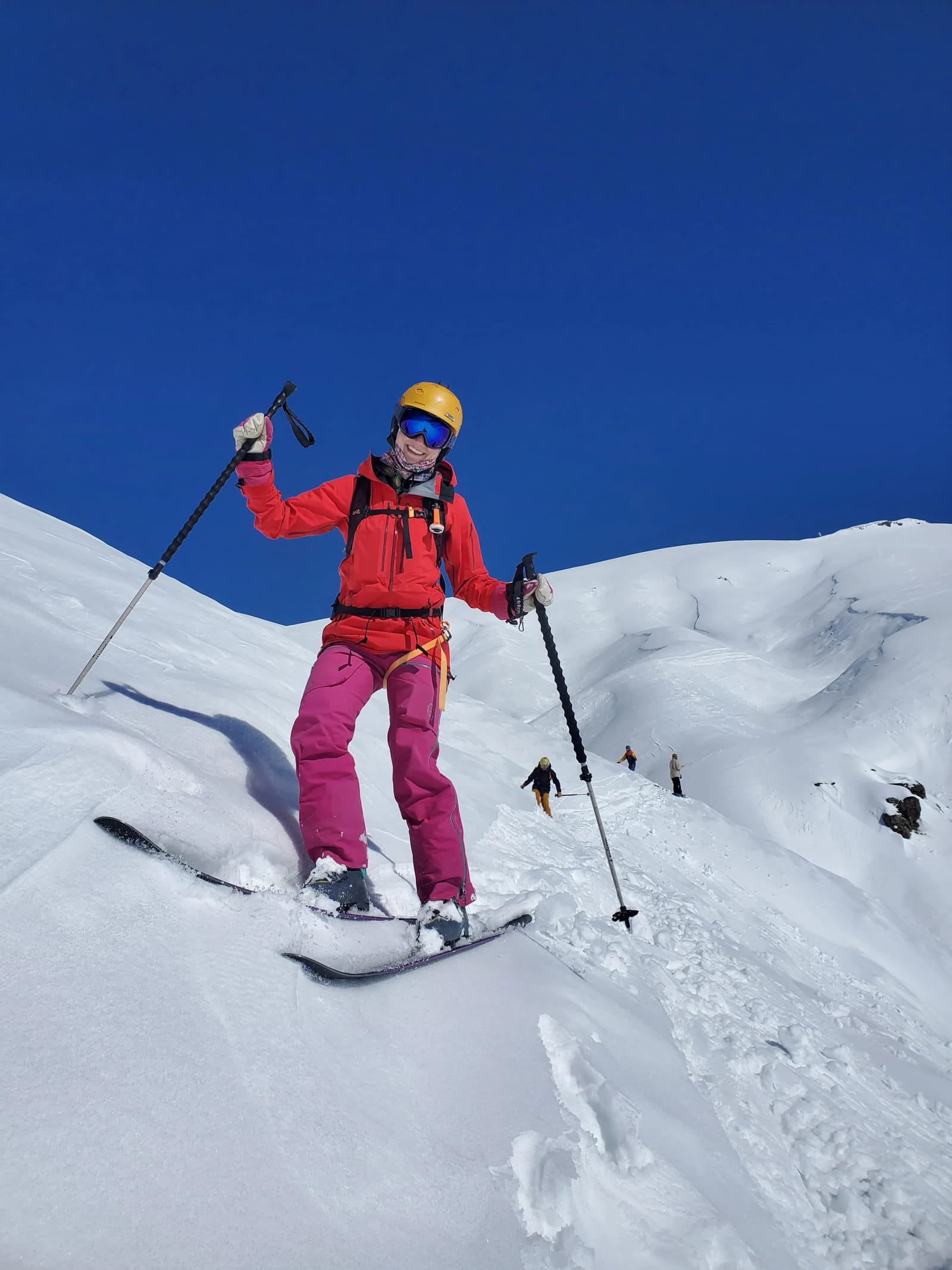 A skier in a red jacket on a snowy Gudauri slope under a blue sky
