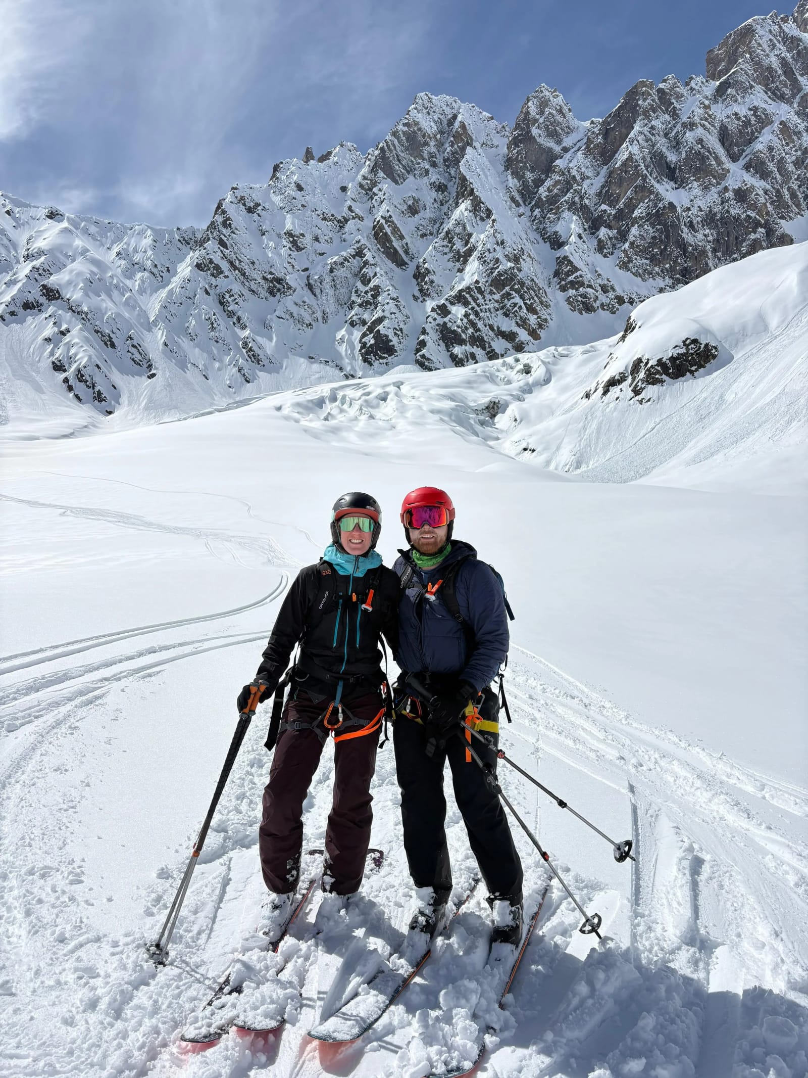 Two skiers below steep snowy mountain walls in Gudauri