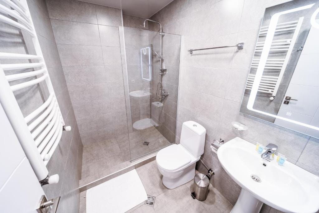 Guesthouse bathroom with a glass shower, toilet, sink and heated towel rail
