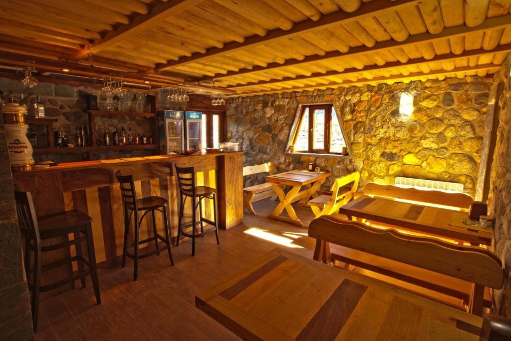 Guesthouse dining room and bar with wooden tables beneath a timber ceiling