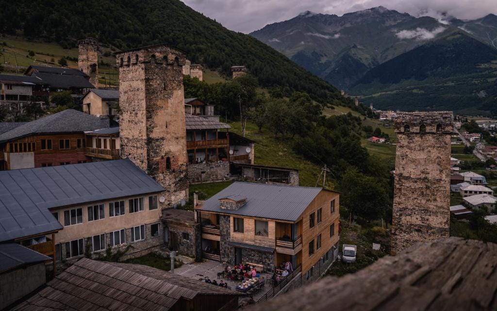 Guesthouse in Mestia among stone Svan towers, with forested mountains behind