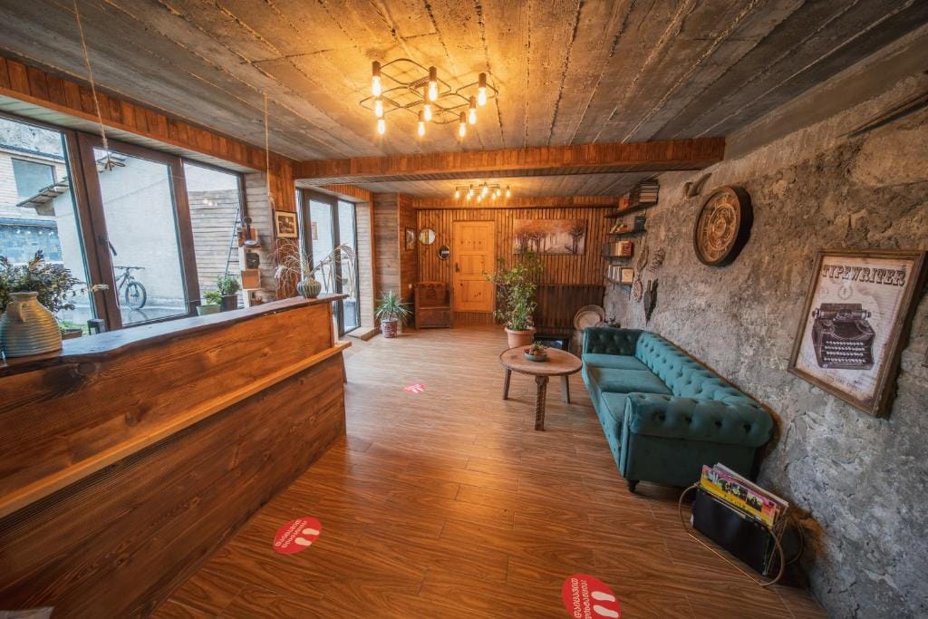 Guesthouse lobby with a wooden reception desk, stone walls and a teal sofa