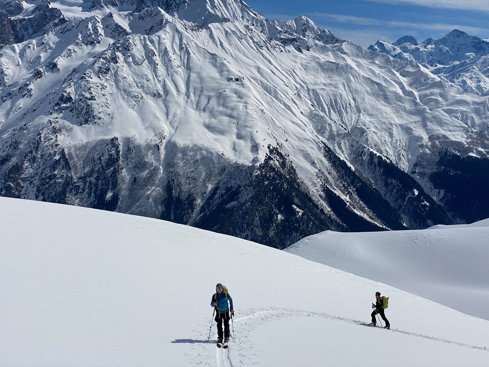 Ski tourers climbing below snow-covered peaks in Svaneti